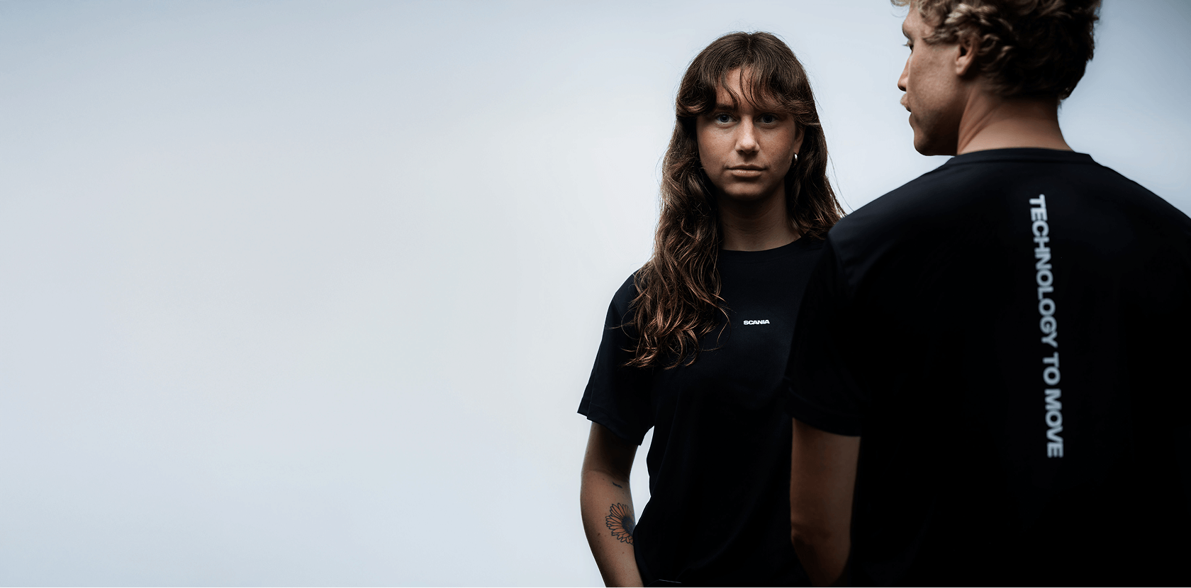 Man and woman standing side by side wearing black Scania T-shirts.